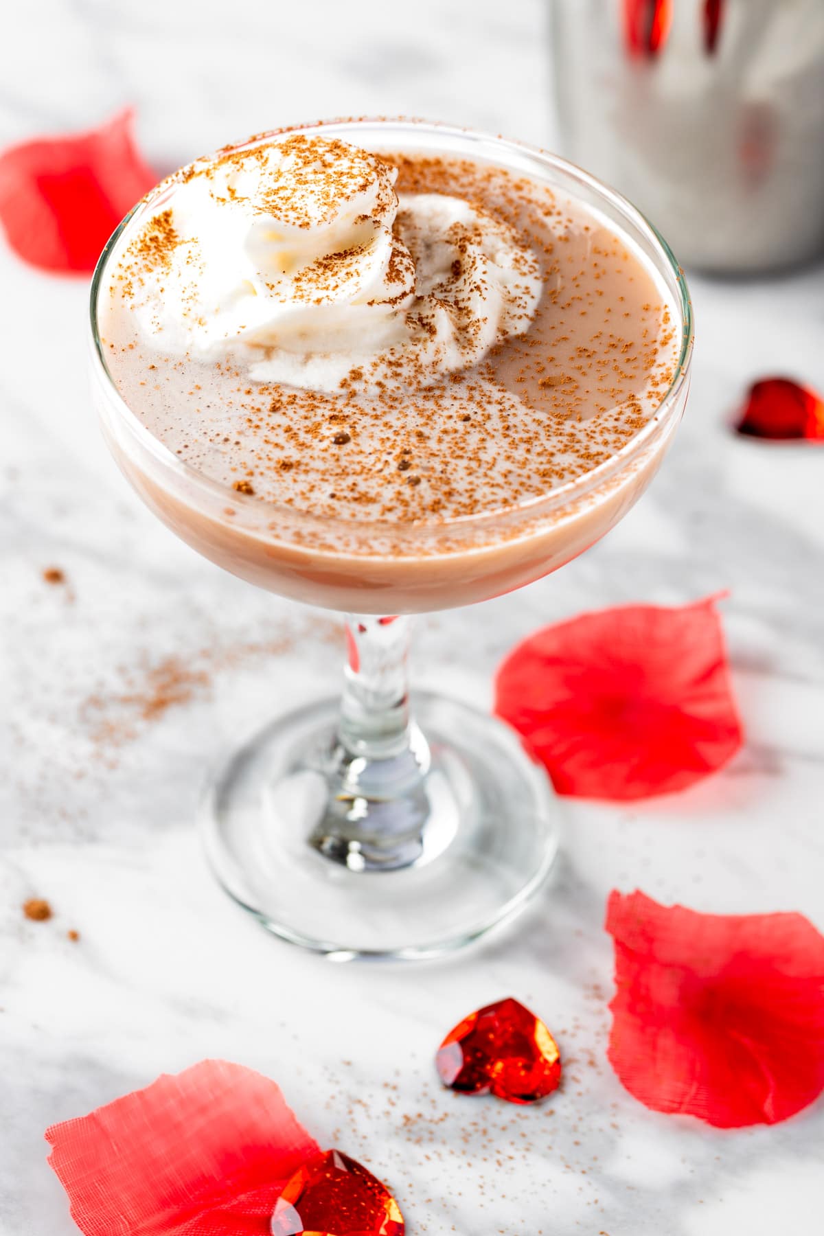 A Strawberry Chocolate Martini topped with whipped cream and a sprinkle of cocoa powder.