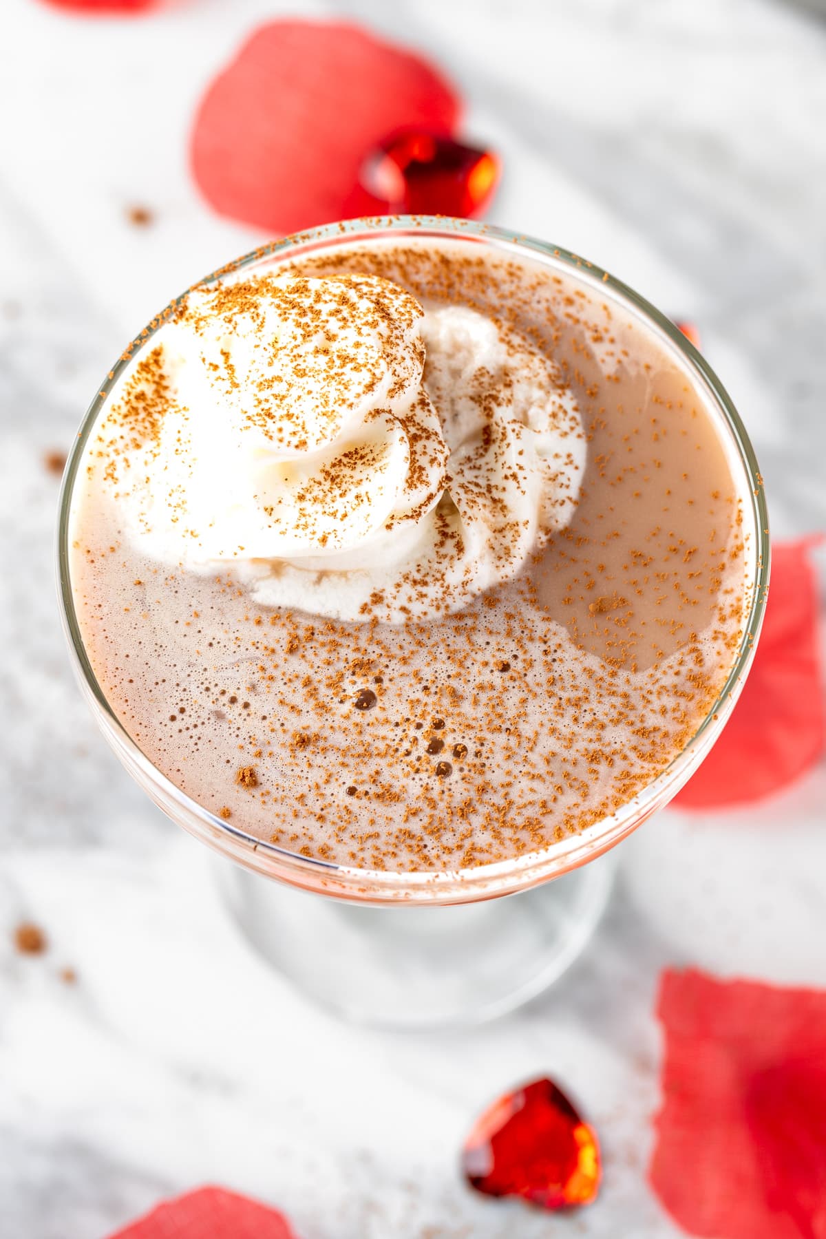 A Strawberry Chocolate Martini topped with whipped cream and a sprinkle of cocoa powder.