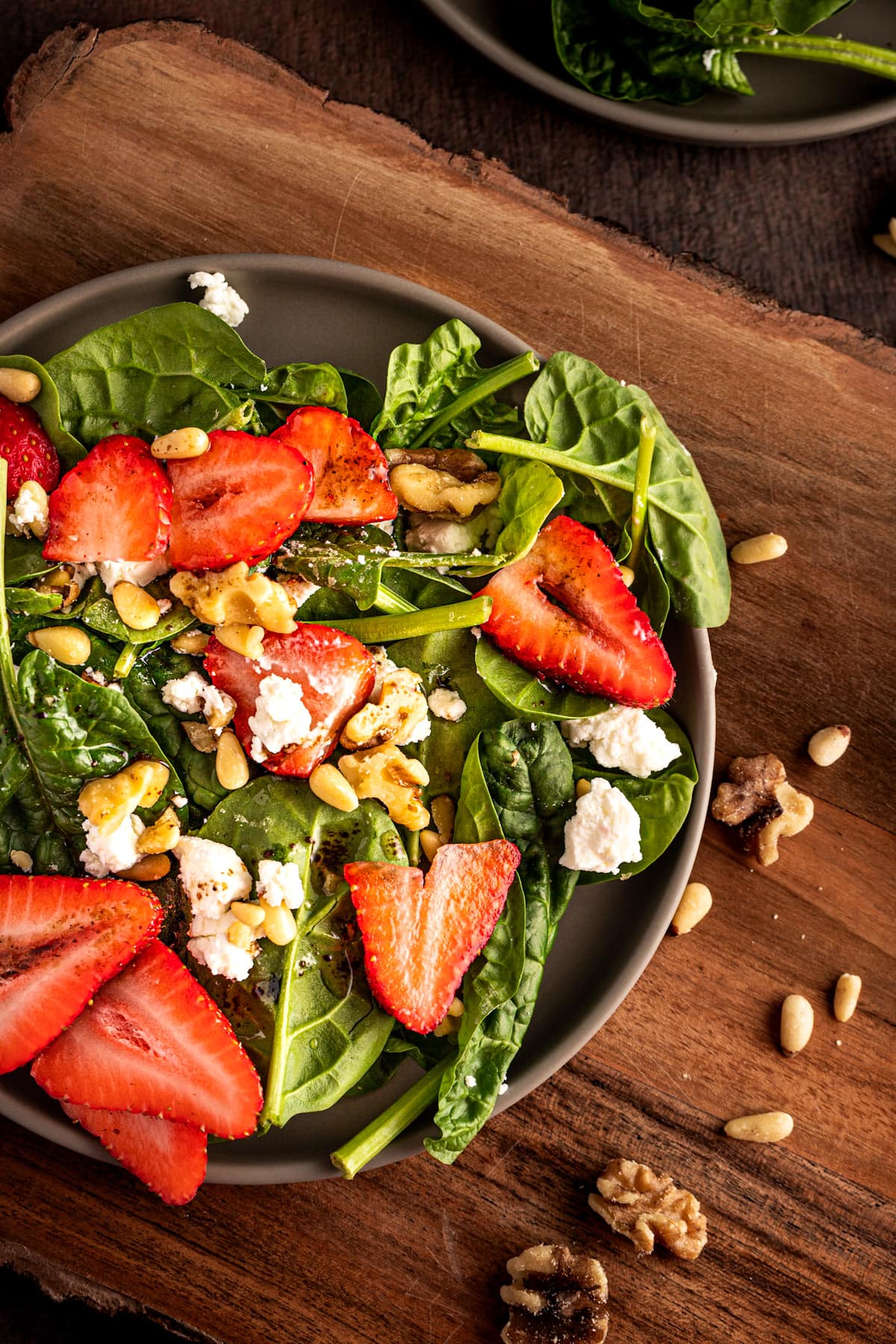Overhead view of the strawberry goat cheese salad, on a wooden table.