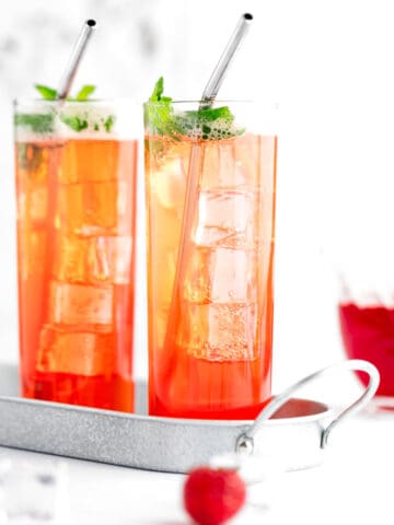 A non alcoholic strawberry mojito garnished with mint, served in a metal tray.