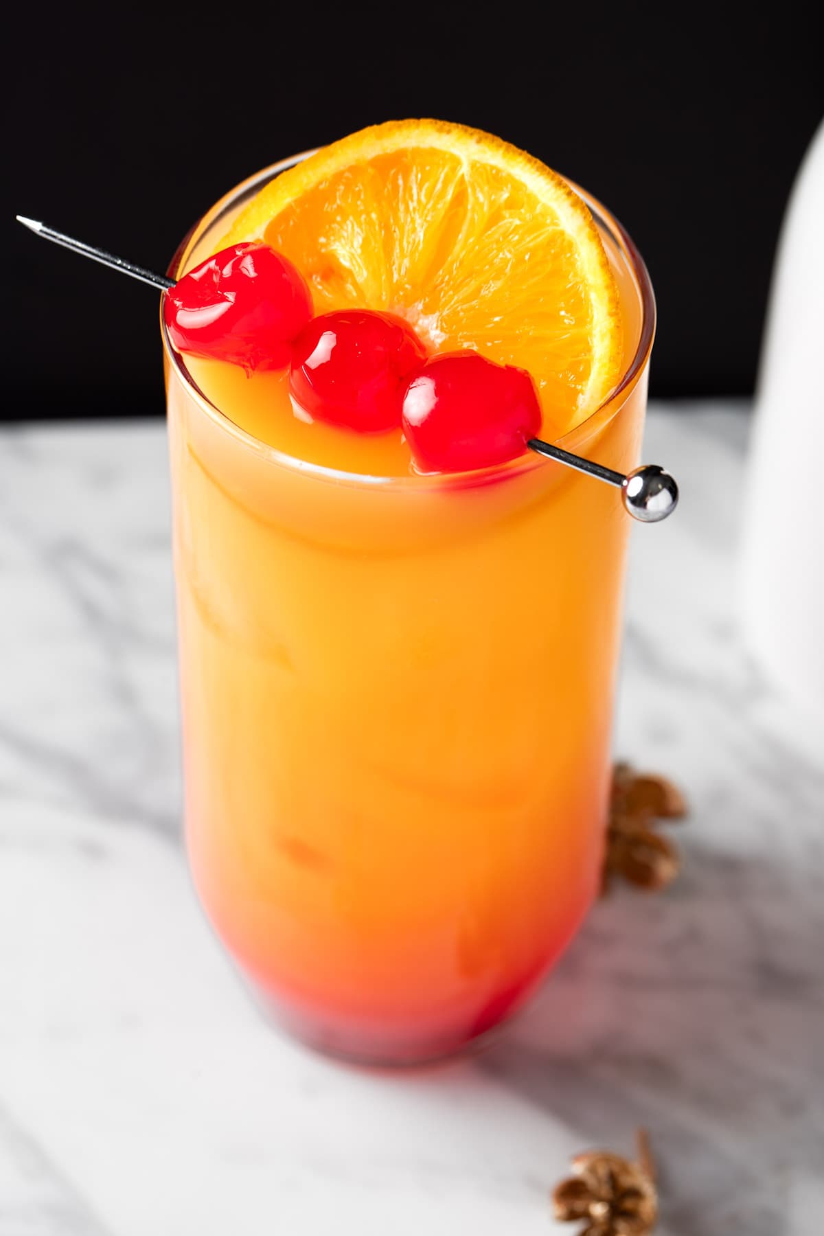 A Tequila Sunrise Without Grenadine Cocktail garnished with maraschino cherries.