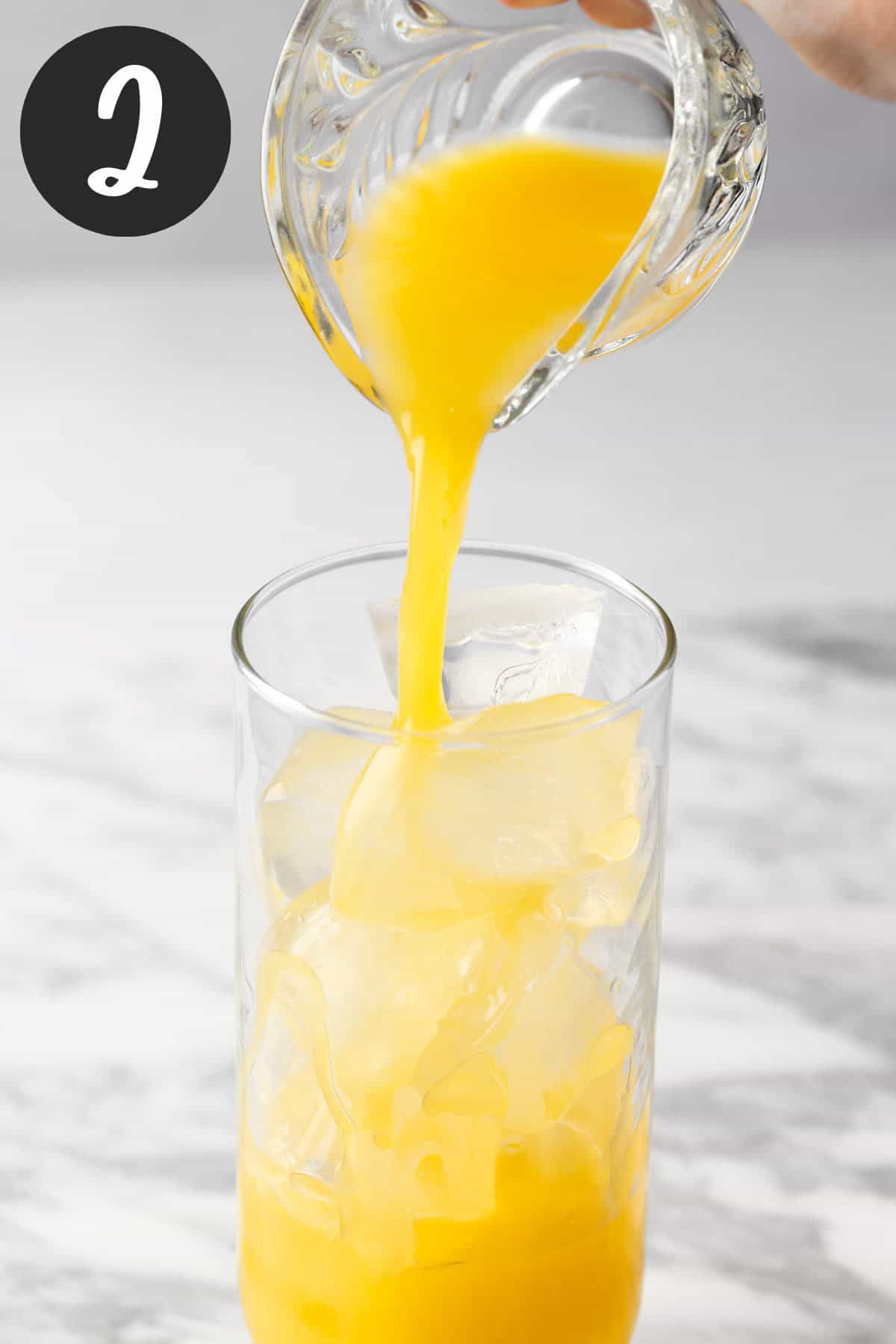 Pouring the tequila and orange juice into a glass filled with ice.