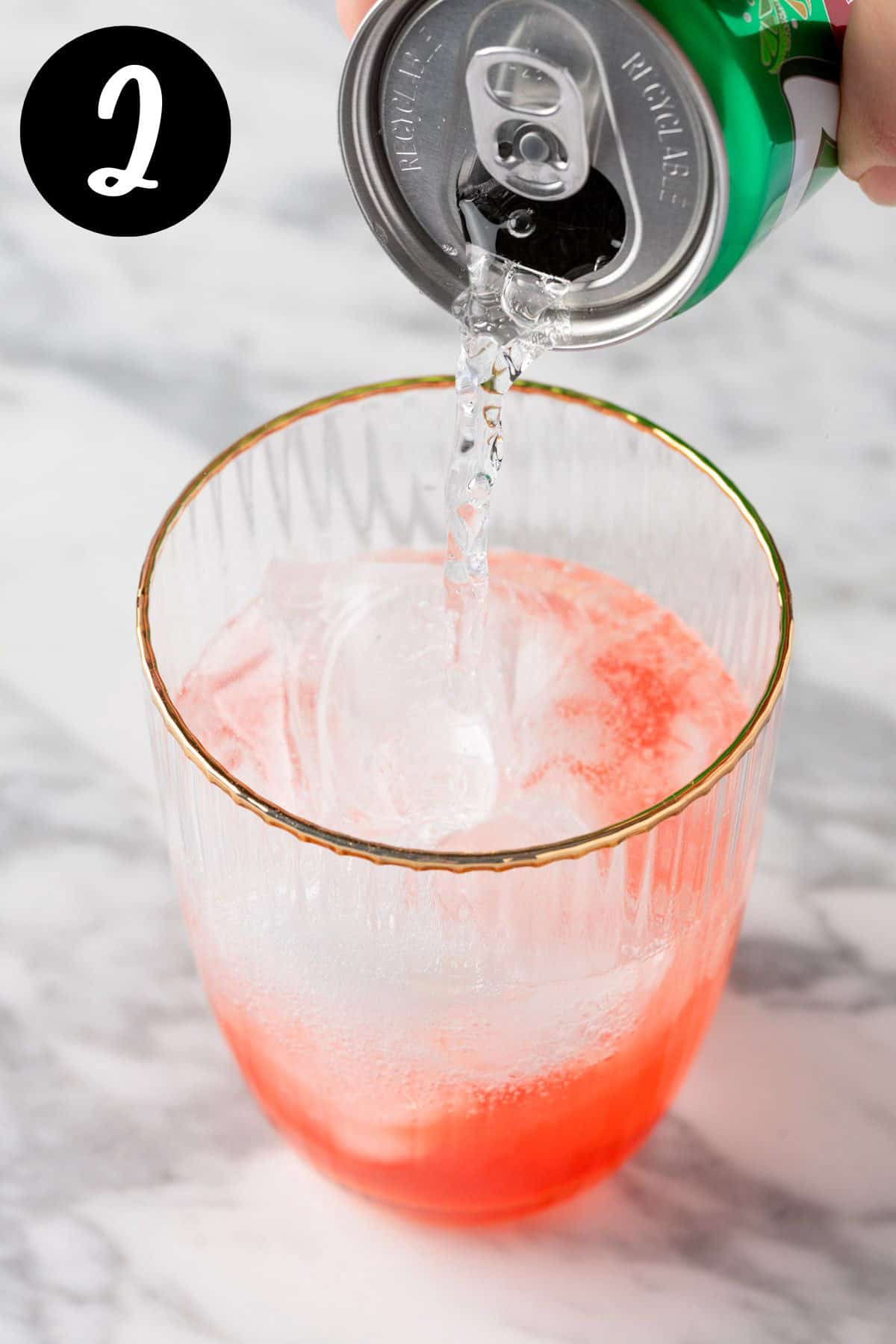 Pouring the lemon-lime soda into the cocktail glass.