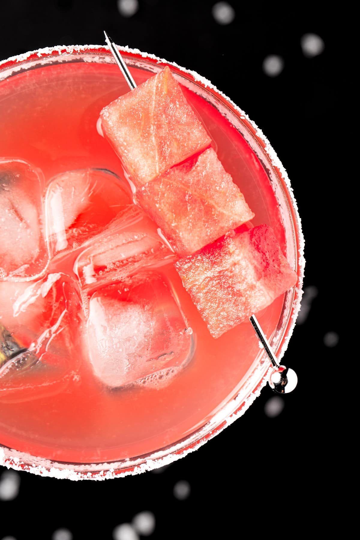 Overhead view of a watermelon margarita garnished with watermelon chunks.