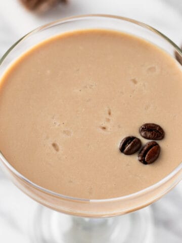 A white chocolate espresso martini garnished with 3 coffee beans.