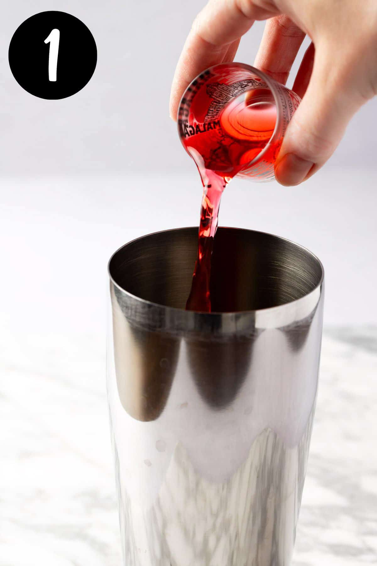 Pouring raspberry syrup into a cocktail shaker.