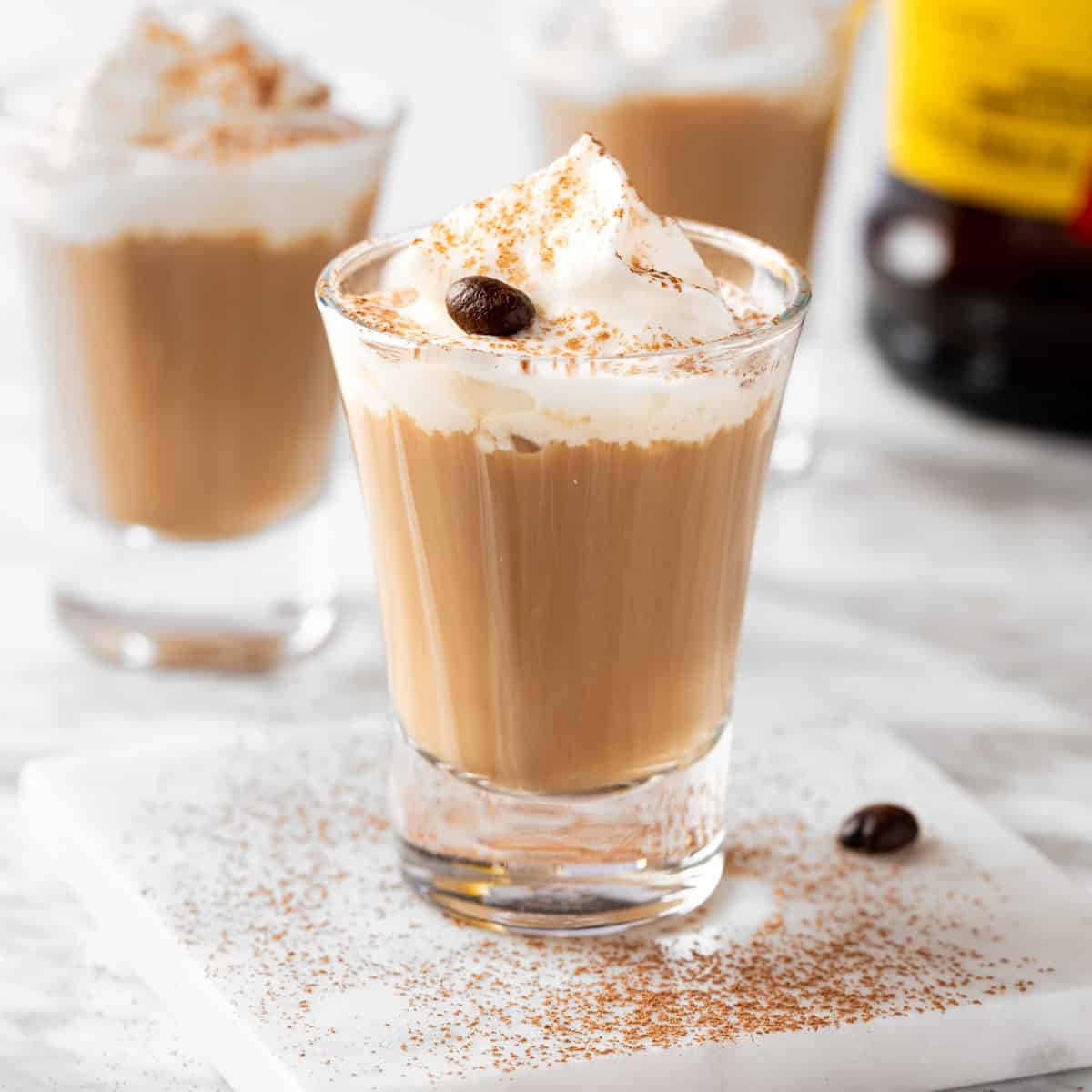 White Russian Shots garnished with whipped cream and a coffee bean.